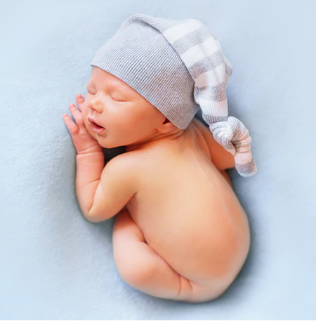 Imagem de um bebê dormindo sobre um tecido azul.  